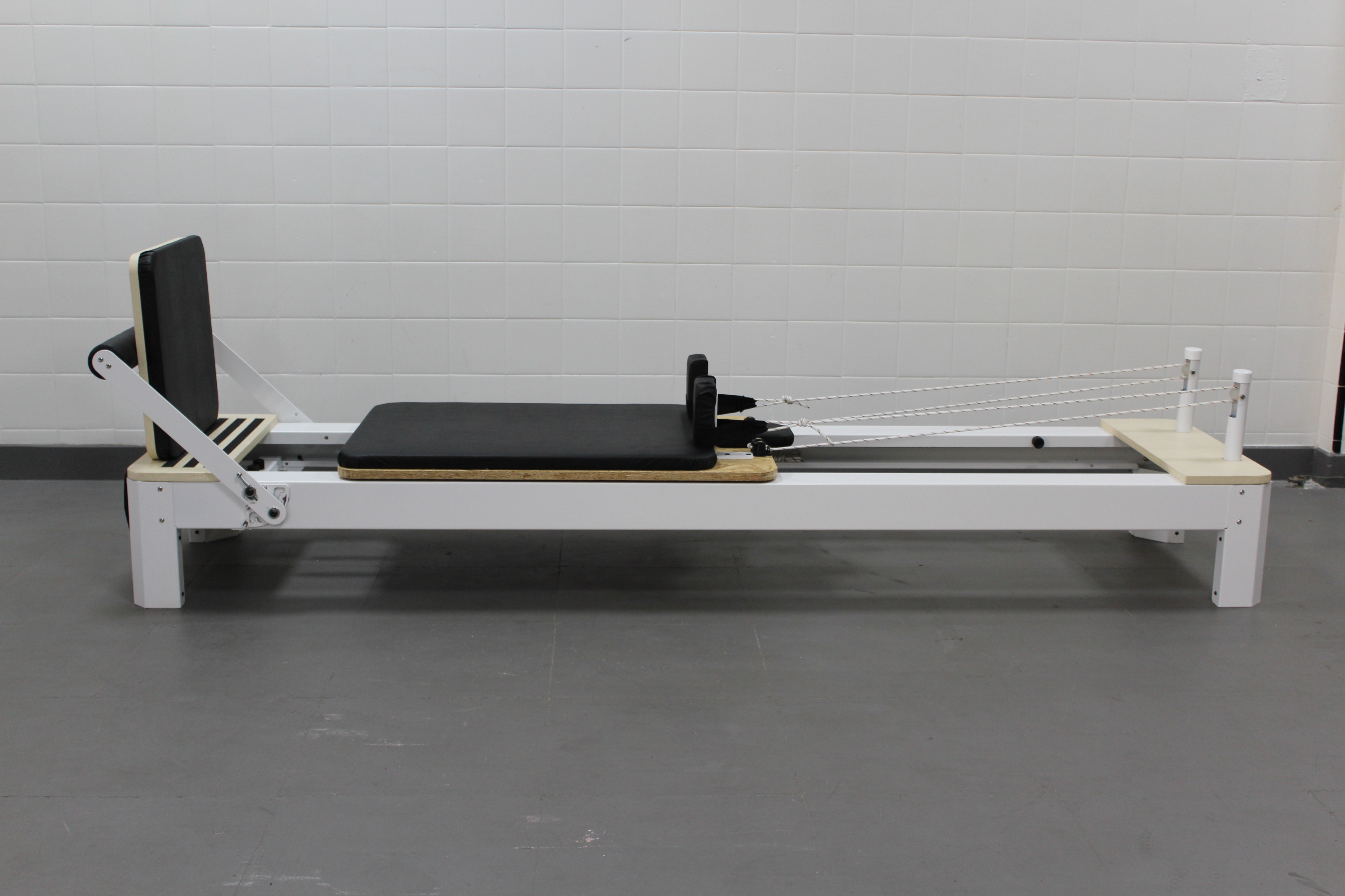 Perfil lateral completo de un reformer de Pilates lima con estructura blanca y carro negro